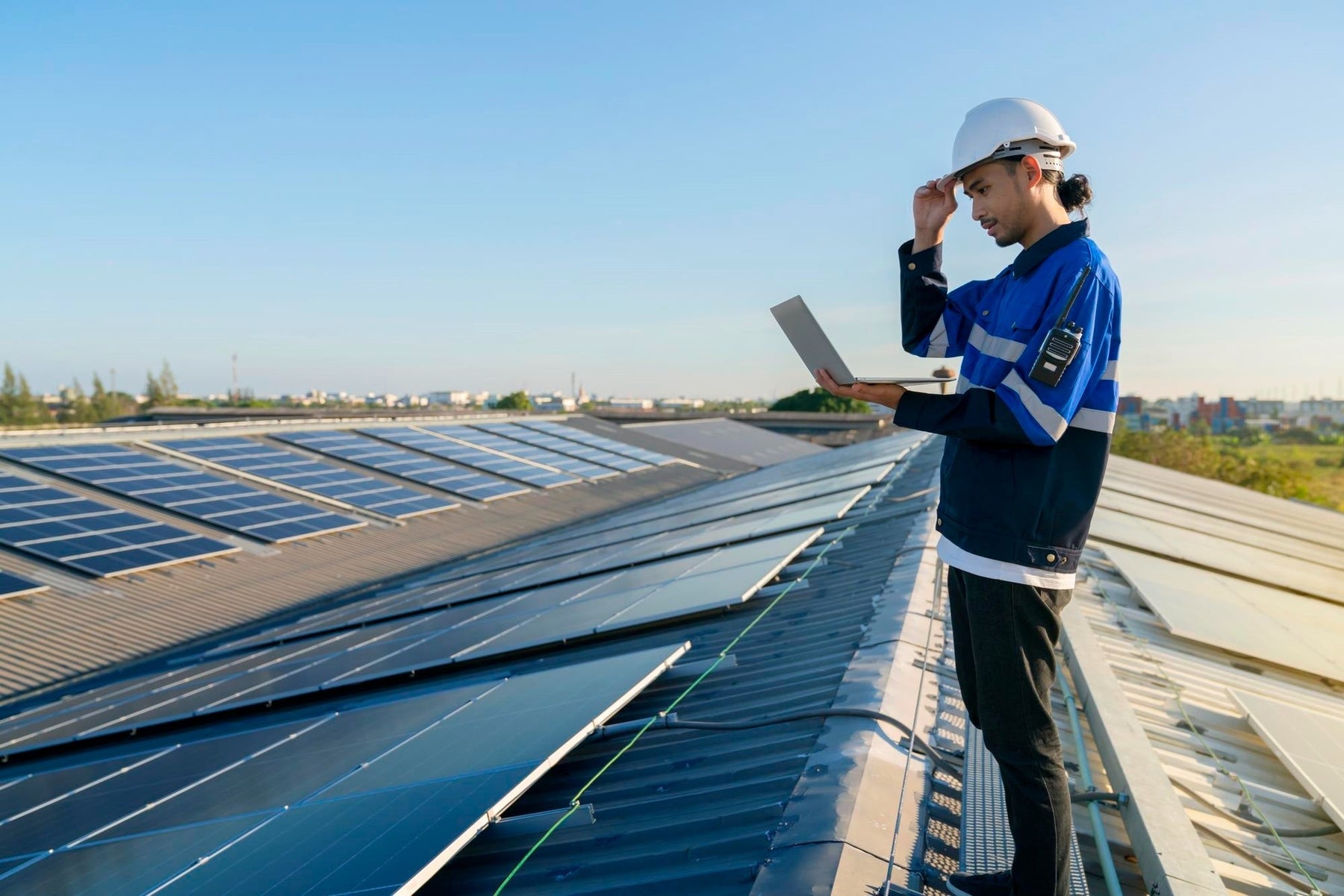 a engineer checking his laptop at the top of solar panels