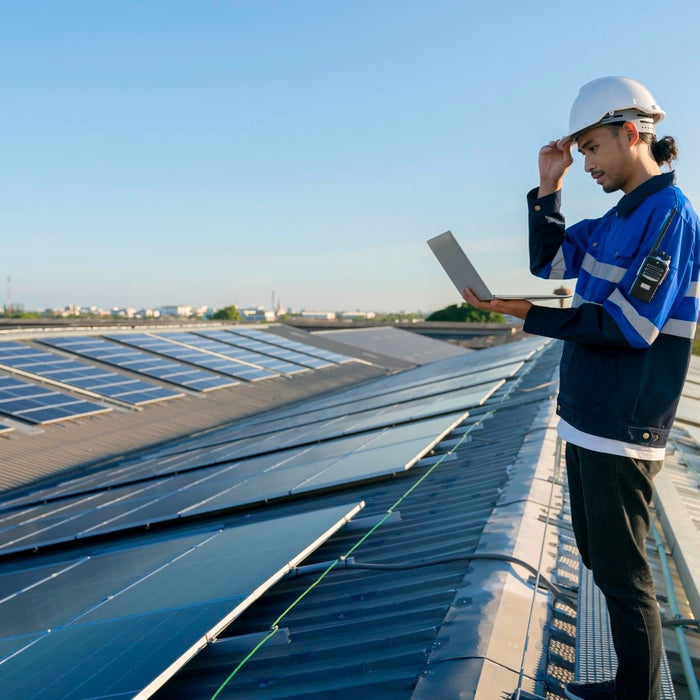 a engineer checking his laptop at the top of solar panels
