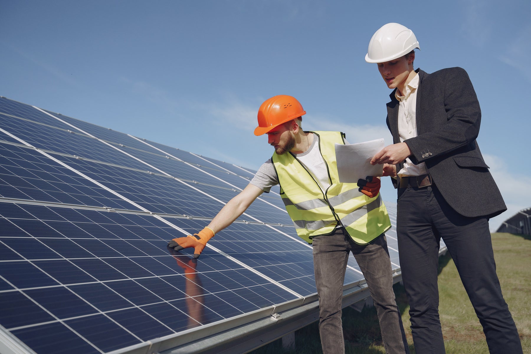 tow person with a paper checking the installed ground solar panels