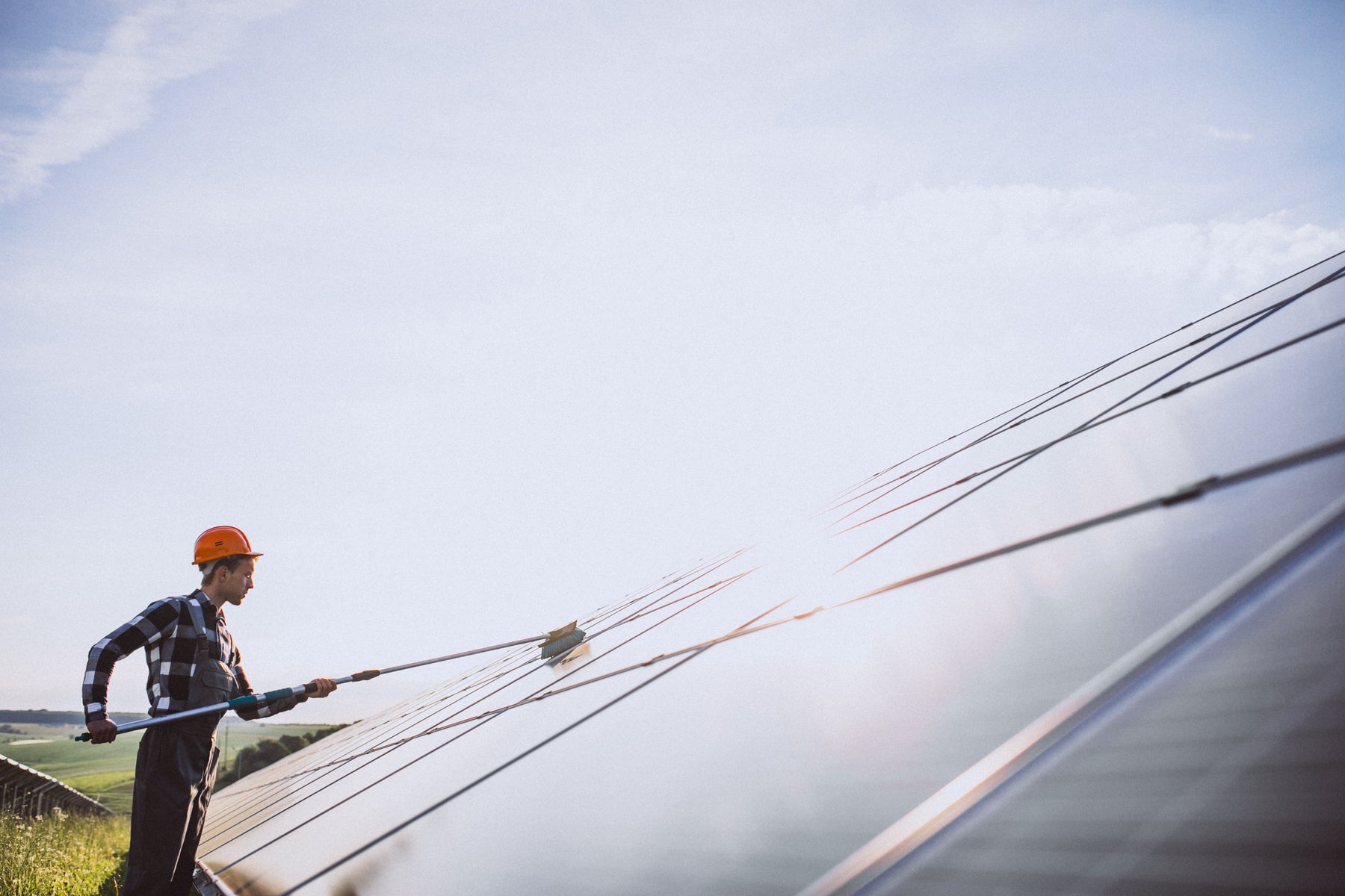a worker cleaning a solar panels under the sun