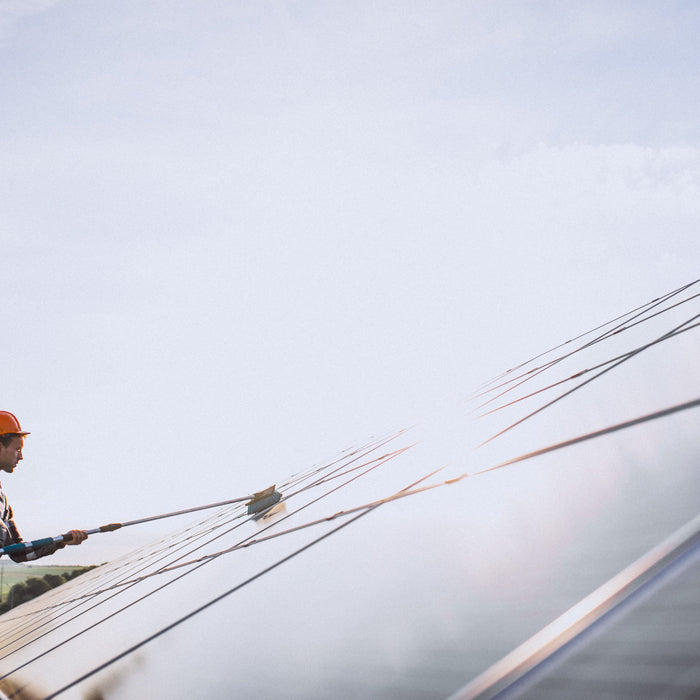 a worker cleaning a solar panels under the sun